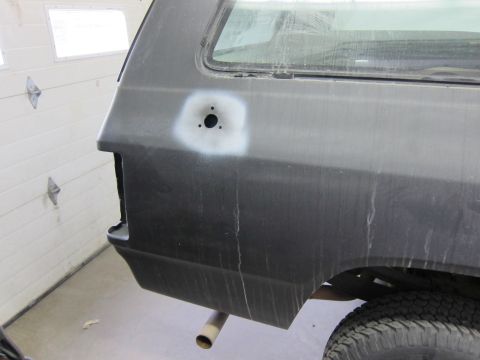 1987 Dodge 1500 - Detail of a vehicle's rear quarter panel, showing a primer spot and mounting holes, possibly for a fuel door or emblem.