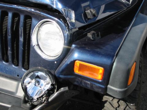 2002 Jeep Wrangler - Front end damage on a blue 2002 Jeep Wrangler, including a broken headlight.