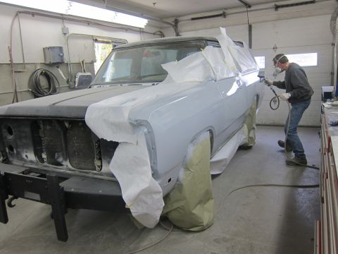 1987 Dodge 1500 - A person sprays primer onto a truck body in a workshop, with parts of the vehicle masked off.
