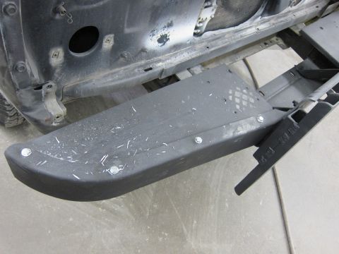 1987 Dodge 1500 - Close-up view of a black step bumper, likely from a truck, with visible bolts and signs of use.