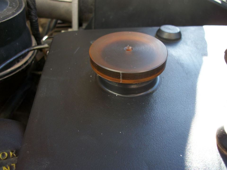 Black engine cover with a brown circular cap and a black button