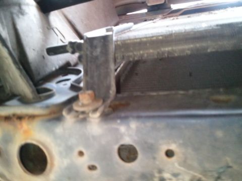 1994 Ford Bronco - Close-up of a radiator mounting bracket, showing rust on the vehicle frame.