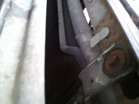 1994 Ford Bronco - A close-up view shows an exhaust pipe secured by a metal bracket, with visible rust on the components.