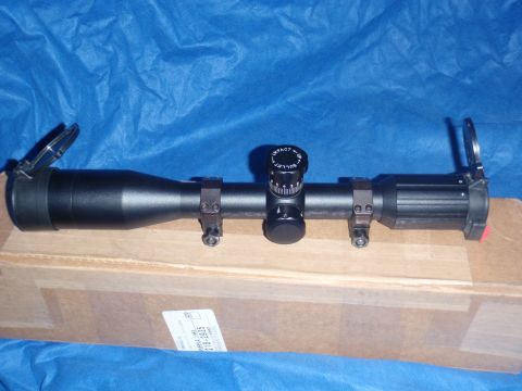 1991 Ford Bronco - A black rifle scope is shown with its turrets and lens caps visible.