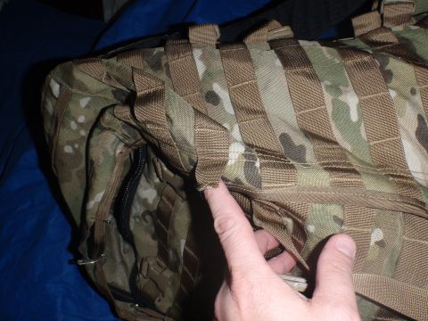 1991 Ford Bronco - A finger points to a damaged strap on a camouflage backpack MOLLE webbing.
