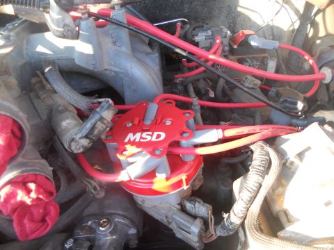 1991 Ford Bronco - Close-up of an engine's ignition system, an MSD distributor and red spark plug wires.
