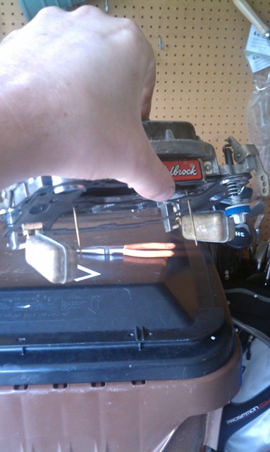 1978 Ford Bronco - A hand holds a Holley carburetor with a red Edelbrock label, likely for an automotive repair or modification.