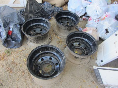 1987 Suzuki Samurai - Four used black steel wheels are shown for sale, with debris scattered around them.