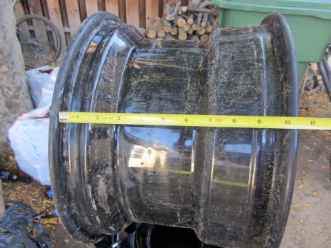 1987 Suzuki Samurai - A black steel wheel is shown with a yellow measuring tape indicating its width. The wheel appears to be for an off-road vehicle.