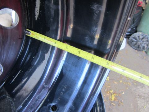 1987 Suzuki Samurai - A yellow tape measure is used to measure the width of a black car fender. Some text is visible on the fender.