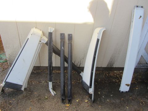 1987 Suzuki Samurai - Collection of white vehicle parts, including doors and roll bar components, displayed outdoors.