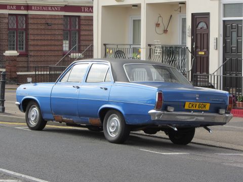 1968 Ford Mustang - Blue sedan with visible rust on the lower body panels and a black vinyl roof is parked curbside.