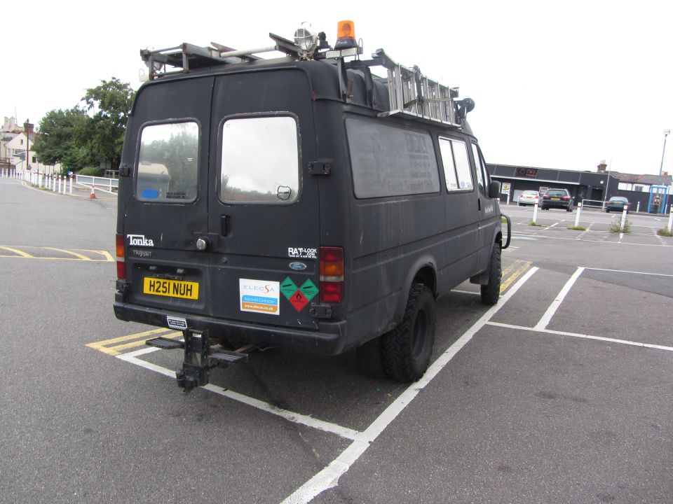 Black van with ladder rack, parked in a lot