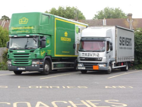 1968 Ford Mustang - A green Scania truck and a silver DAF truck are parked in a lot marked for lorries and coaches.