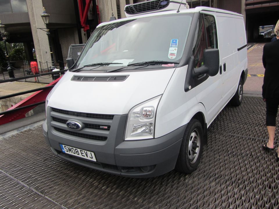 White Ford Transit van with license plate SM08 EVJ parked on a metal grate platform