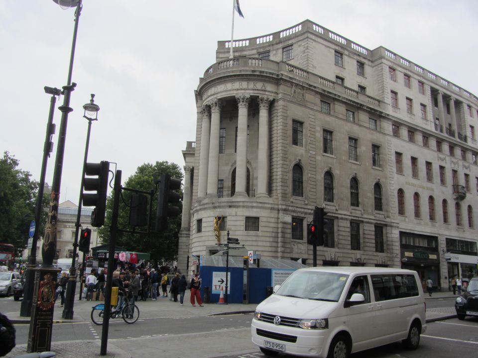 Street scene with a white van, traffic lights, and a large stone building with columns