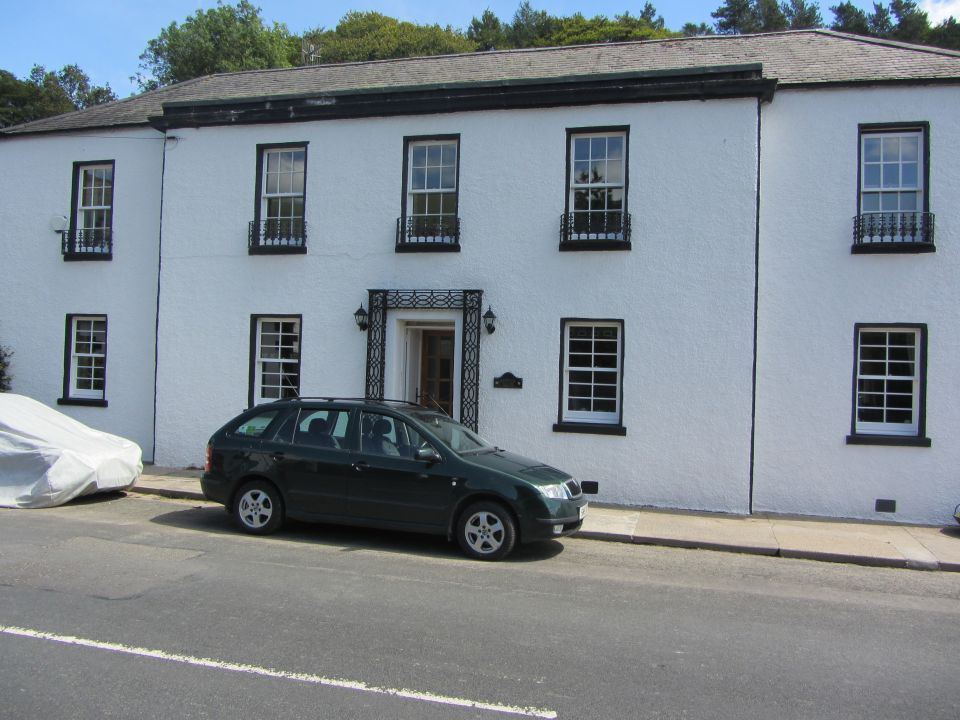 Dark green station wagon parked on a street in front of a white building