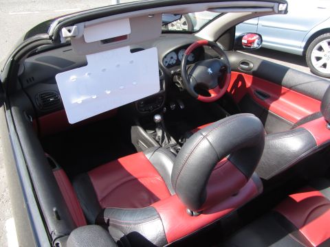 1968 Ford Mustang - Interior view of a Peugeot 206 CC convertible, showing the red and black leather seats and dashboard.