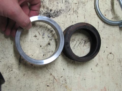 1993 Ford F-250 - A hand holds a new aluminum exhaust gasket beside a used, rusted gasket on a wooden surface.