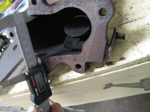 1993 Ford F-250 - A close-up of a rusty exhaust manifold part being measured with a digital caliper.