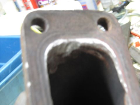 1993 Ford F-250 - Close-up of a metal exhaust manifold flange with visible welding marks and two mounting holes.