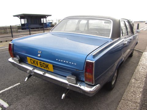 1968 Ford Mustang - Rear view of a blue Vauxhall sedan with a black vinyl roof, parked curbside.