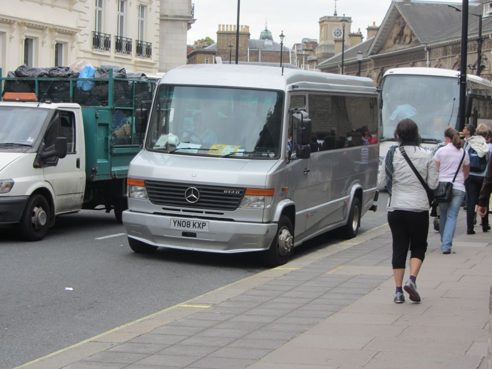 Silver Mercedes-Benz van with license plate YN08 KXP parked on street next to a truck