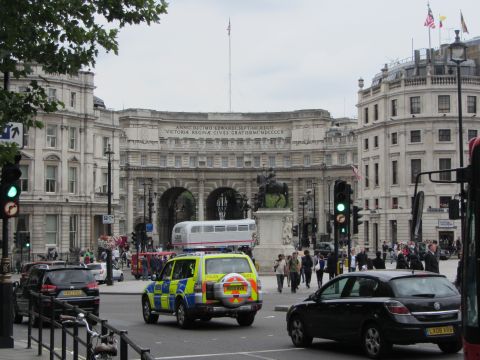 1968 Ford Mustang - A police vehicle is seen in traffic on a London street, with a large historical archway in the background.