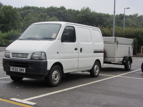 1968 Ford Mustang - White Suzuki Carry van towing a trailer, parked in a lot.