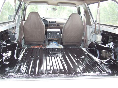 1996 Ford Bronco - The interior of a vehicle shows exposed metal flooring and two front seats.