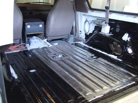 1996 Ford Bronco - The interior of a vehicle is being worked on, with the floor stripped and painted blacked out.