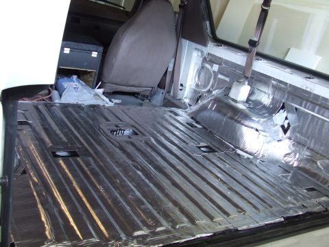 1996 Ford Bronco - The interior of a vehicle is being prepared for soundproofing, with insulation covering the floor and lower panels.