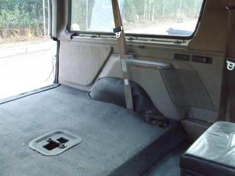 1996 Ford Bronco - The rear cargo area of a vehicle, showing the carpeted floor and interior paneling.
