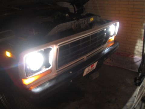 1979 Ford Bronco - Front view of a 1979 Ford Bronco, hood is open, headlights are illuminated.