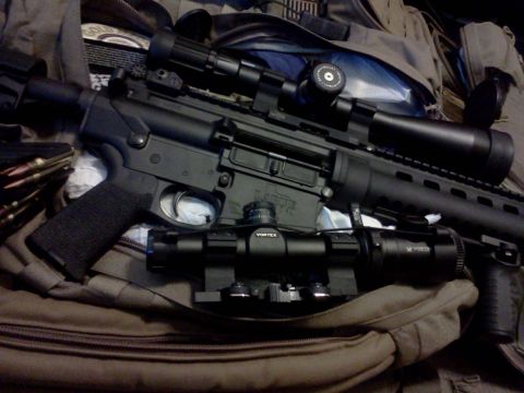 1996 Ford Bronco - An AR-15 style rifle is shown with a scope and bipod attached, resting on a bag.