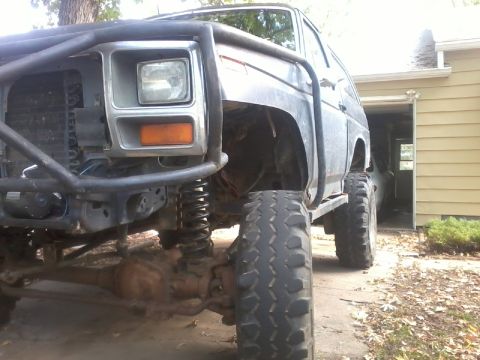1986 Ford Bronco - This heavily modified SUV features oversized tires and a prominent roll cage, obscuring its original year and model.