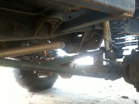 1986 Ford Bronco - Close-up of vehicle undercarriage, focusing on suspension and drivetrain parts.