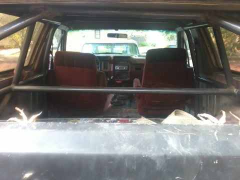 1986 Ford Bronco - Interior view of a vehicle a roll cage and red seats, with a visible dashboard and gear shifter.