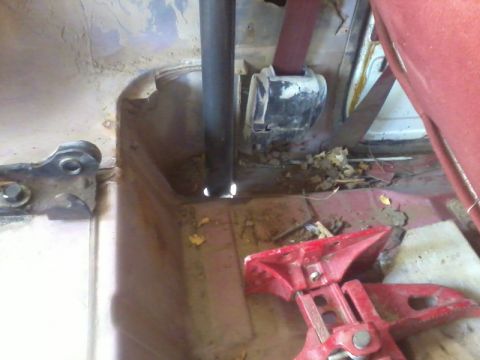 1986 Ford Bronco - The interior of a vehicle is visible, a seatbelt and a metal pole, with debris on the floor.