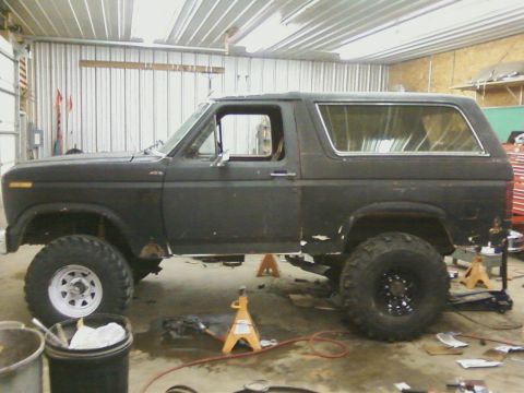 1986 Ford Bronco - This Ford Bronco is raised on jack stands, showing its undercarriage and suspension components during a maintenance session.