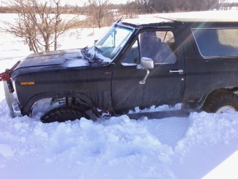 1986 Ford Bronco - This vehicle is stuck in a snowy area, with snow piled high around its tires and body.