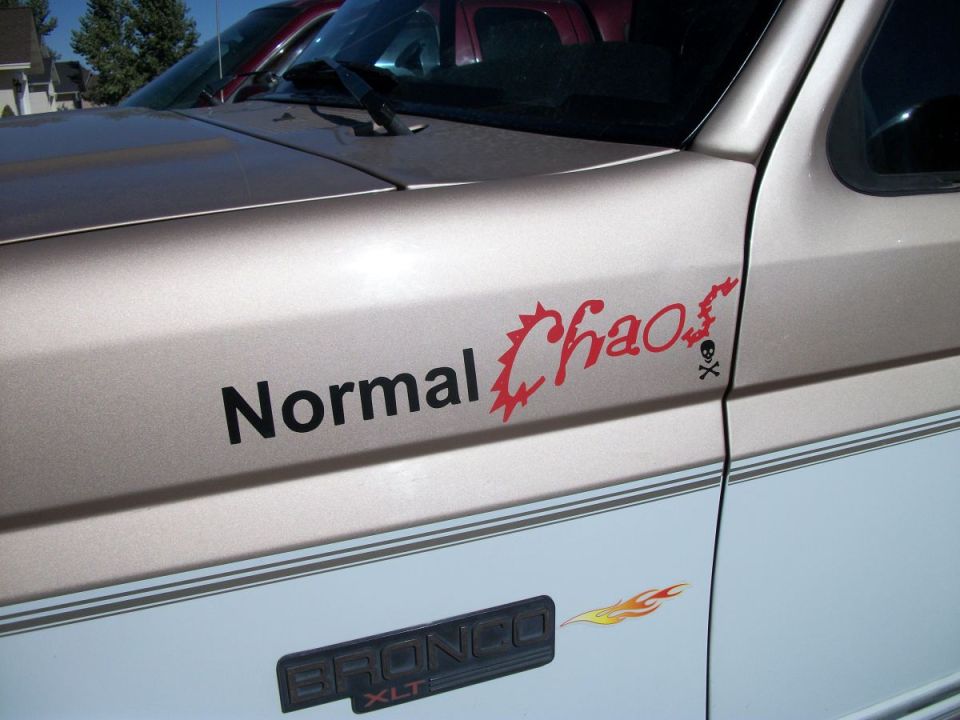 Side view of a beige and white Ford Bronco with "Normal Chaos" decal and "BRONCO XLT" badge