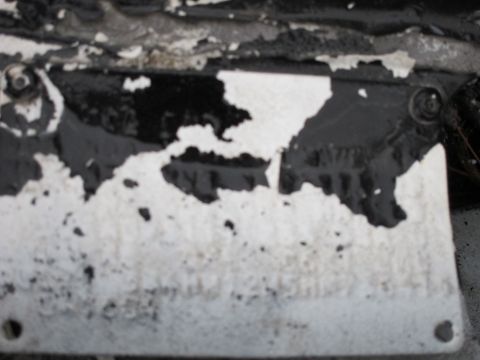 1987 Dodge 1500 - A close-up of a damaged metal plate with peeling paint reveals obscured details.