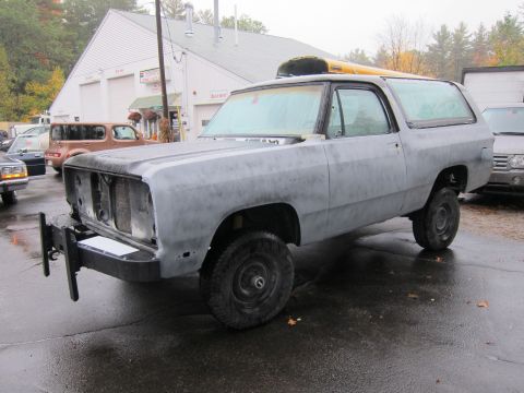 1987 Dodge 1500 - This Dodge Ramcharger is in primer and missing its front grille, parked on a wet asphalt lot.