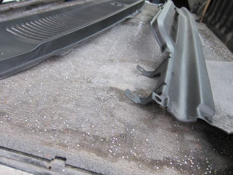 1987 Dodge 1500 - These are two plastic automotive trim pieces, possibly from the interior or exterior, lying on a work surface.