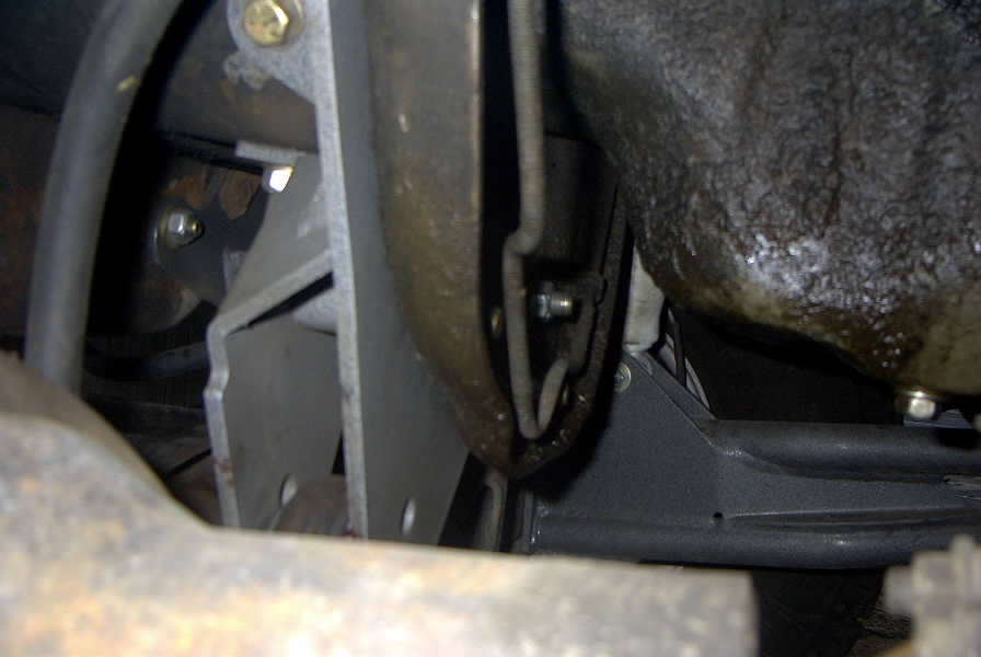 Underside view of a 1994 Ford Bronco showing oil pan, metal bracket, crossmember and exhaust components