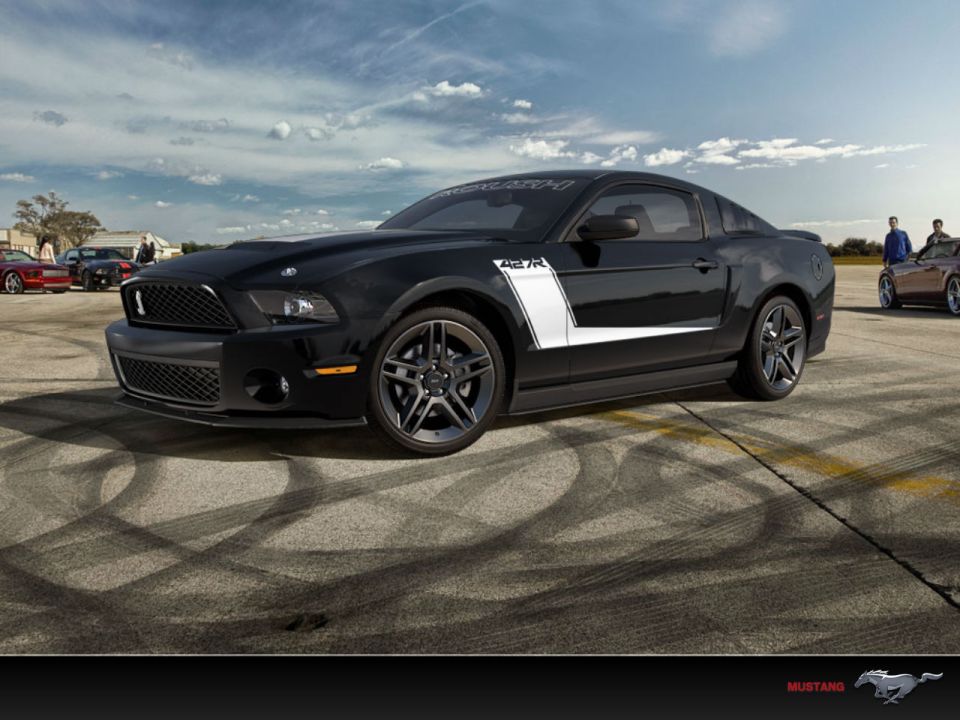 Black 2012 Ford Mustang 427R with white side stripe parked on asphalt with tire marks. Other cars and people in background
