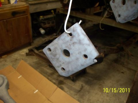1990 Ford Bronco - A metal bracket with several holes, possibly a suspension or mounting component, is shown hanging and being prepped for work.