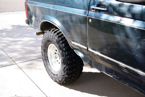 1995 Ford Bronco - Close-up of the rear tire and fender of a 1995 Ford Bronco, showing aftermarket wheels and tires.