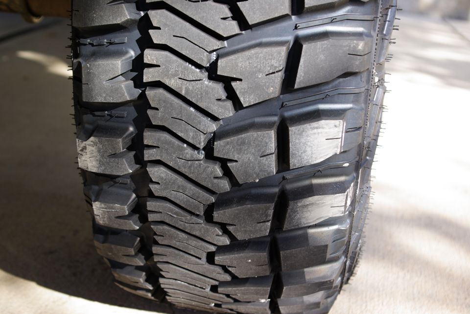 Close-up of a black off-road tire tread with deep grooves and aggressive block patterns